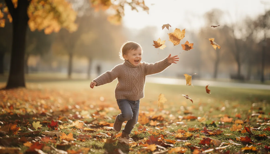 Na zdjęciu widać dziecko ubrane w sweter z wełny merino, bawiące się podczas jesiennego spaceru w parku. Sweter, wykonany z wyjątkowo delikatnych włókien wełny merynosów, zapewnia mu ciepło i komfort w chłodniejsze dni.